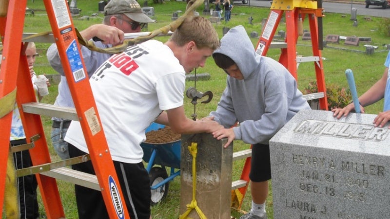 Marshfield High School students reposition a grave marker at the Marshfield Pioneer Cemetery