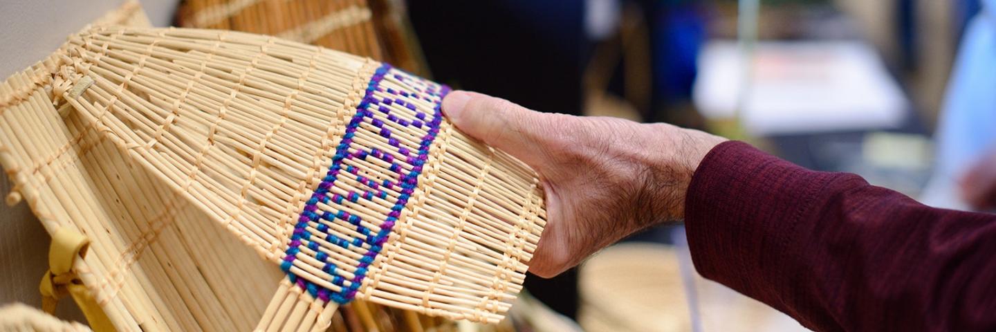 Hand reaching for woven cradle board made by Sara Barton