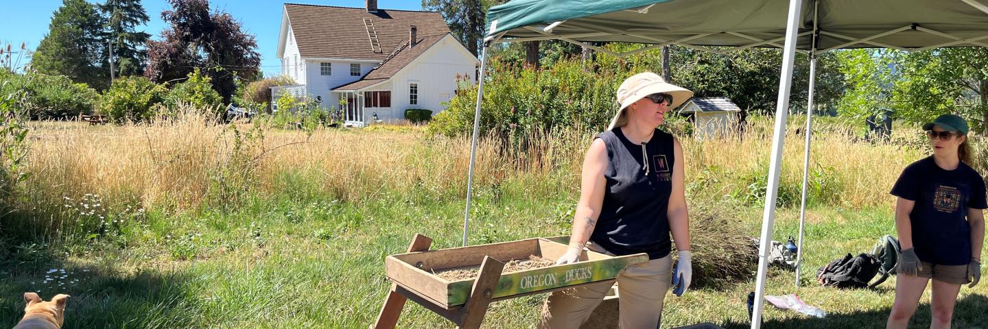 Archaeology students work in the field in front of the Applegate house