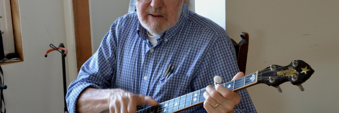 Hobe Kytr, a white man in a blue shirt, plays the banjo
