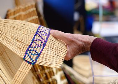 Hand reaching for woven cradle board made by Sara Barton