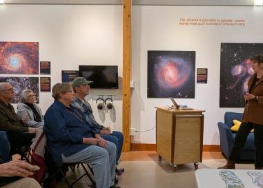 A small group of people listen to Katelyn McDonough speak