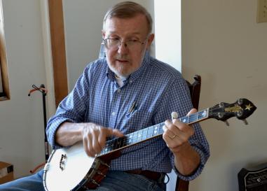 Hobe Kytr, a white man in a blue shirt, plays the banjo