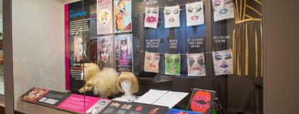 Case filled with wigs, dress, and makeup face wipes on display.