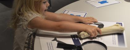 Girl standing next to table holding a leg bone.