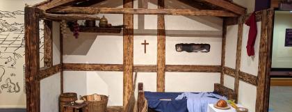 Medieval European house replica with wood beams, white walls and a bed.
