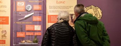 Two people looking at Magic for Love exhibit panel