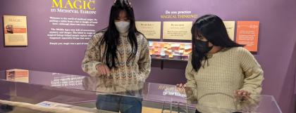 Two visitors viewing a large Unicorn Horn in a case.