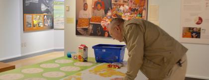 Man bends over a map activity with a large picture of a smiling family in the background