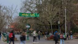 Students walking by the ASUO Special Election Banner displayed on 13th Ave. center of campus at the University of Oregon