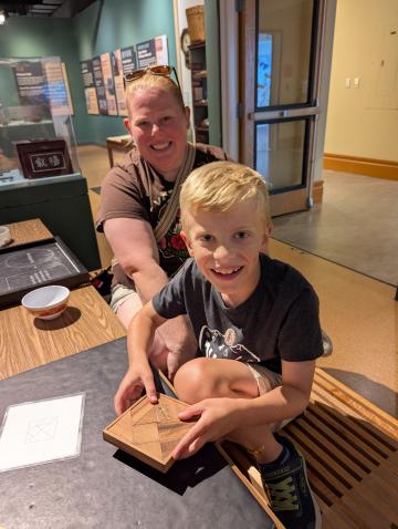 A child and their parent holds a completed tangram puzzle